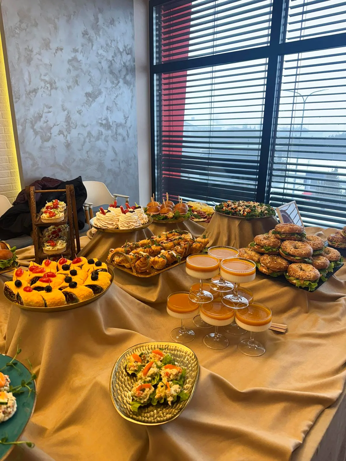 Bufet przy oknie z bajgle, croissantami, panna cotta i sałatkami