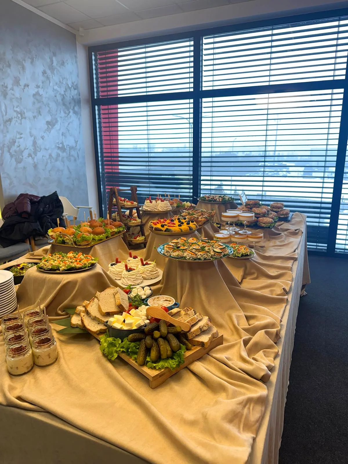 Stół bufetowy z pieczywem, deską serów, ogórkami i bezą pavlova